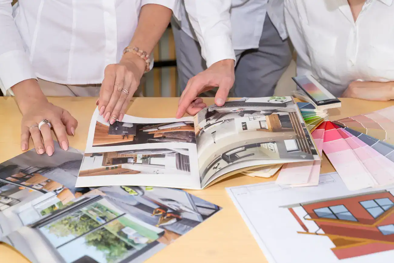 Three people sitting at a desk flipping through a brochure